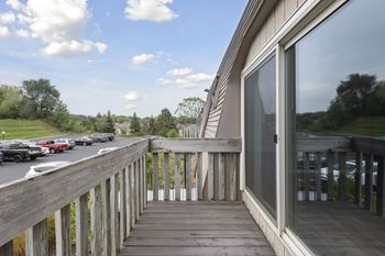 A wooden deck with a railing and a glass door leading to a house.